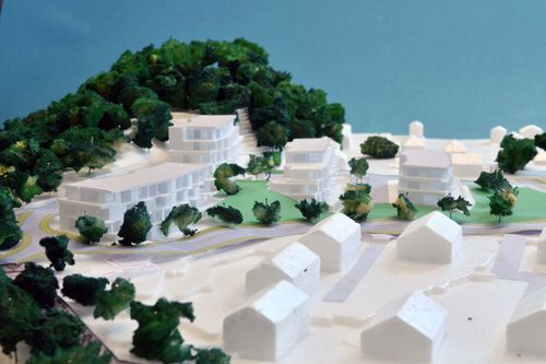 Fysisk modell av planlagt boligområde med terreng, boligblokker og beplantning i skrånende landskap.