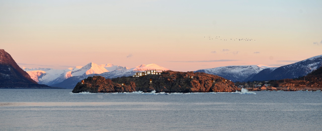 Oversiktsbilde av Furkenholmen med hotell og hytter i landskapet, omgitt av fjord og fjell i kveldssol.