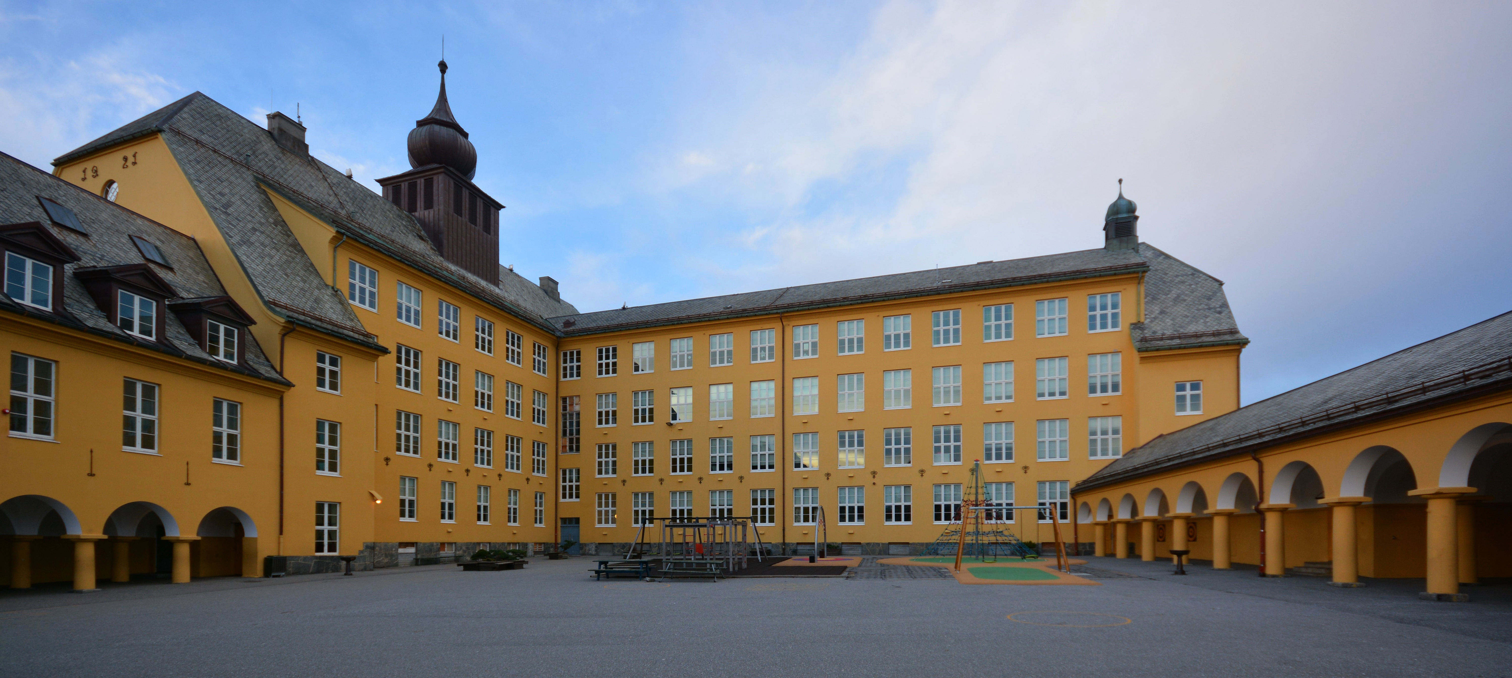 Baksiden av Aspøy skole med skolegård og lekeplass innenfor den U-formede bygningen.