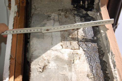 Nærbilde av gammel vindusniche med målestokk og eksponert trekarm.