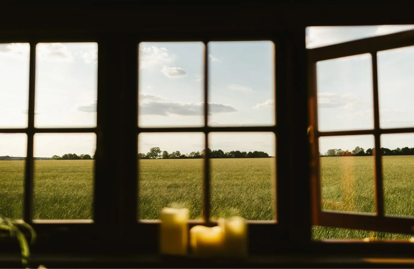 View over the fields from the kitchenette inside the shepherds hut. Candles lit on the windowsill.