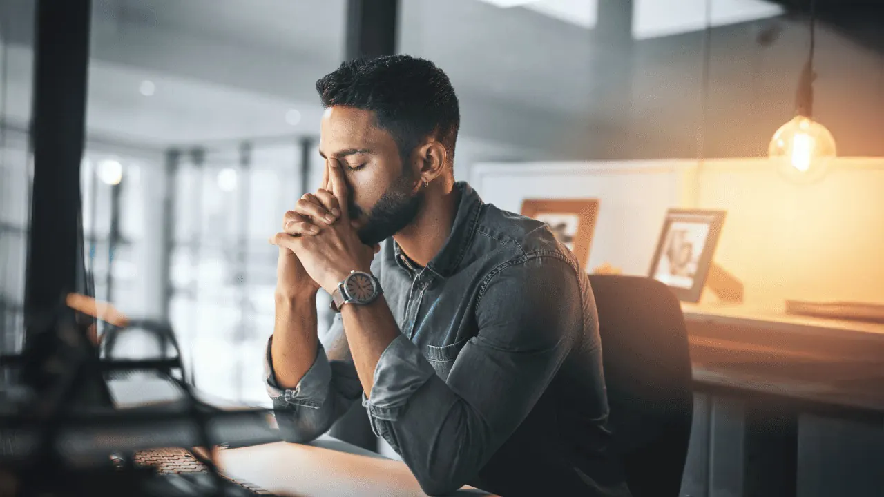 Mann im Büro sitzt nachdenklich am Laptop – Fokus, Stressmanagement und mentale Klarheit im Arbeitsalltag