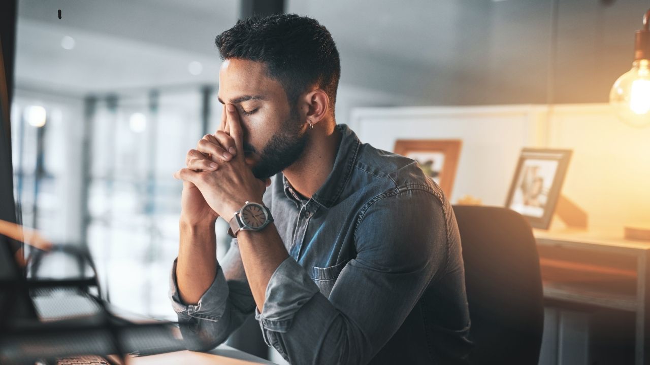 Man in office sitting thoughtfully at laptop – focus, stress management and mental clarity in everyday work