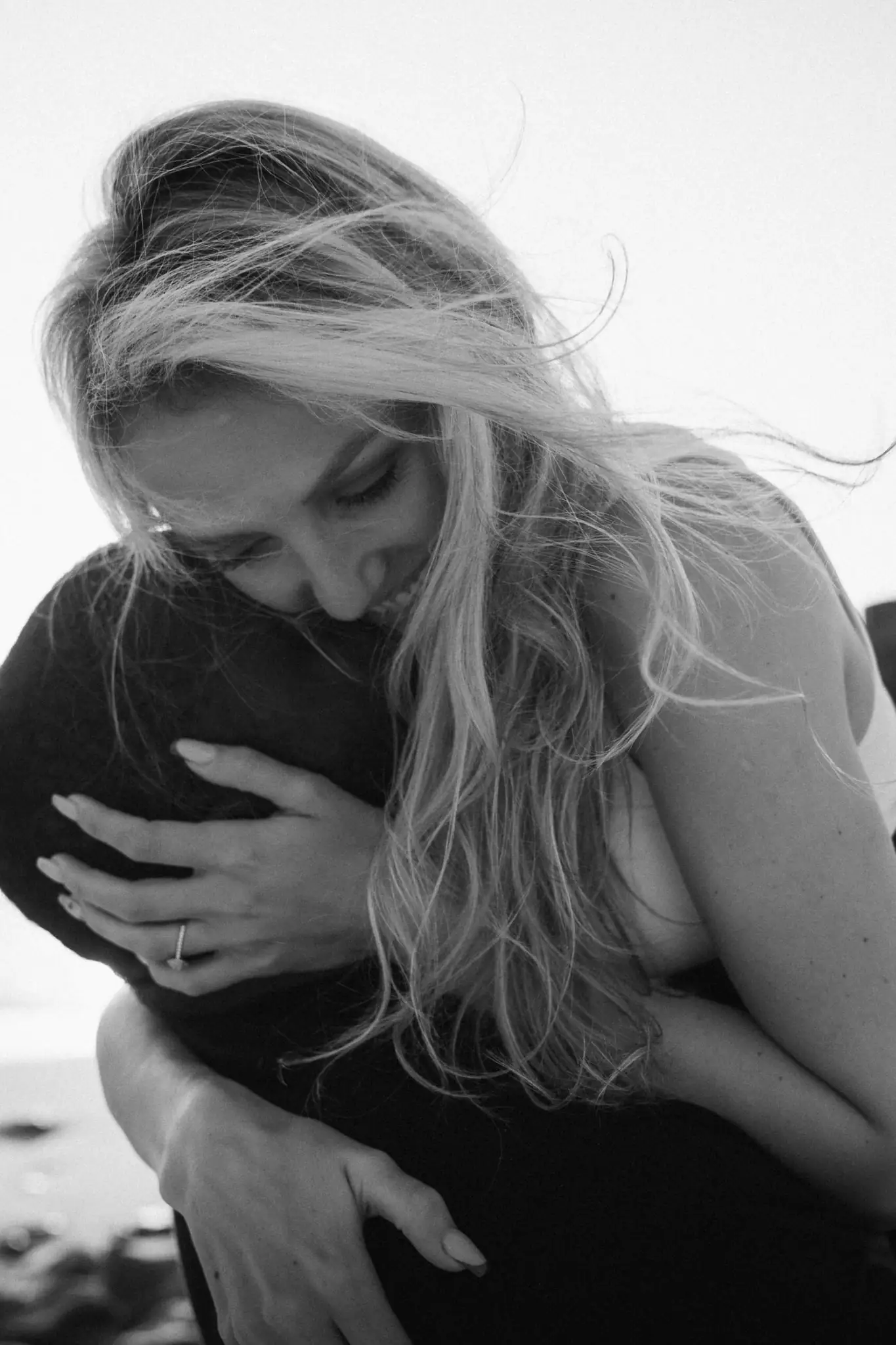 Black-and-white close embrace on the beach, ring visible — couple photographer Camps Bay