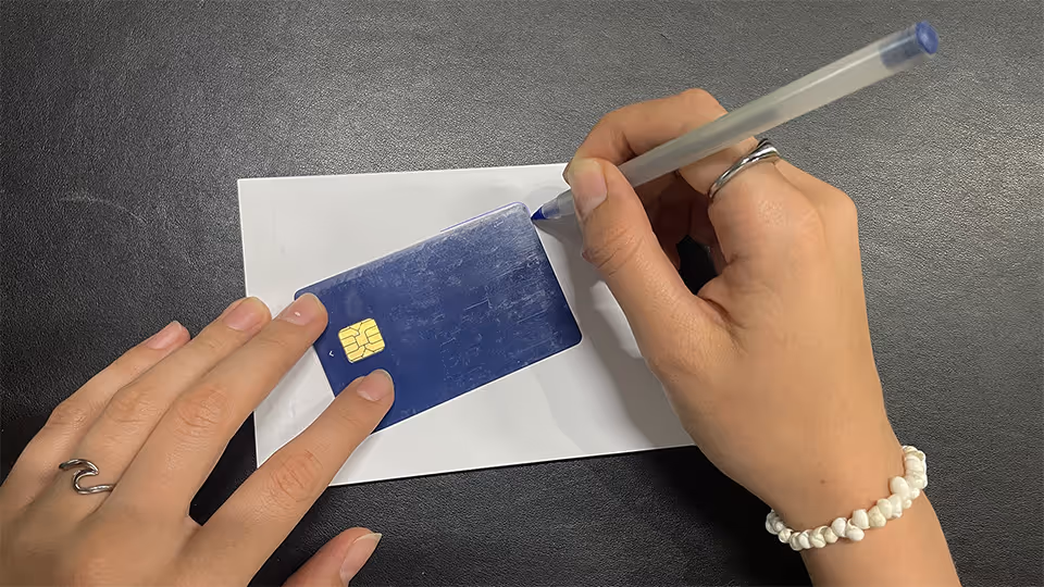 Die Umrisse einer Bankkarte werden auf ein Papier abgezeichnet