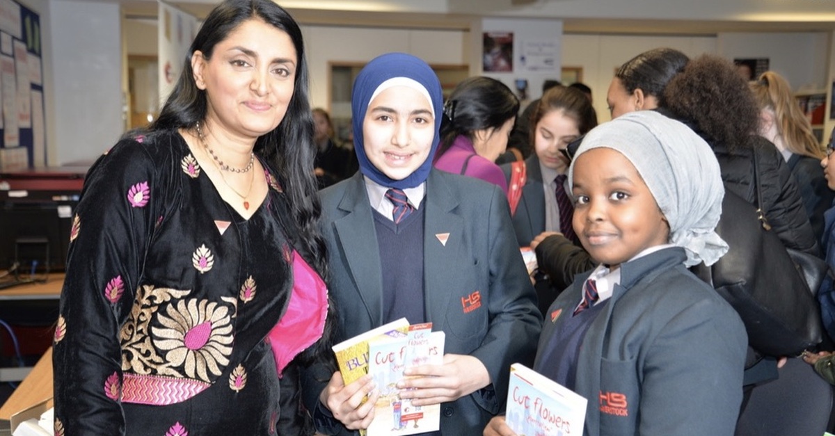 Aneeta Prem MBE with two students holding her safeguarding books But It’s Not Fair and Cut Flowers during a Freedom Charity school session.