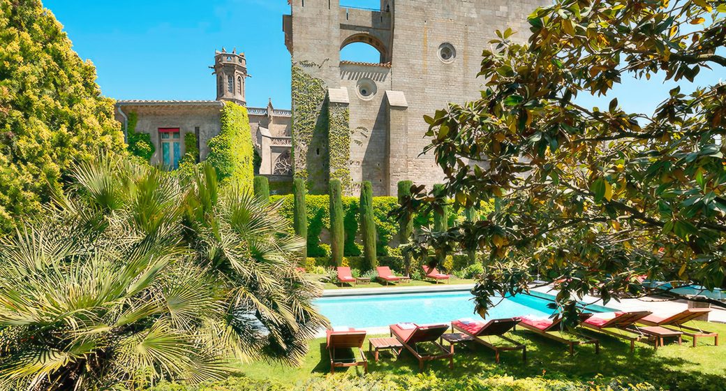 The pool and courtyard garden at Hotel de la Cite, with the medieval basilica towers behind