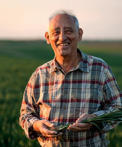 An older man smiling with a field in the background