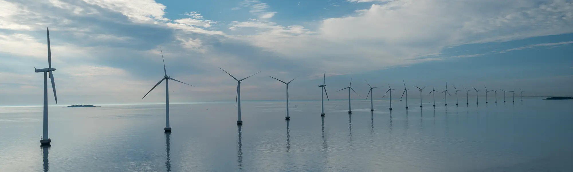 Up close view of offshore windmill with additional windmills and ocean in the background