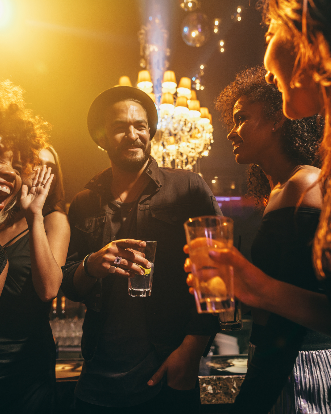 Man blindfolded holding a card while woman smiles beside him during Love at First Sign dating event.
