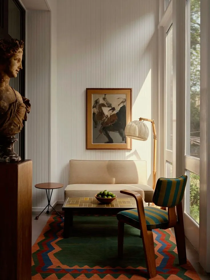 This may contain: a living room filled with furniture and a painting hanging on the wall next to a window