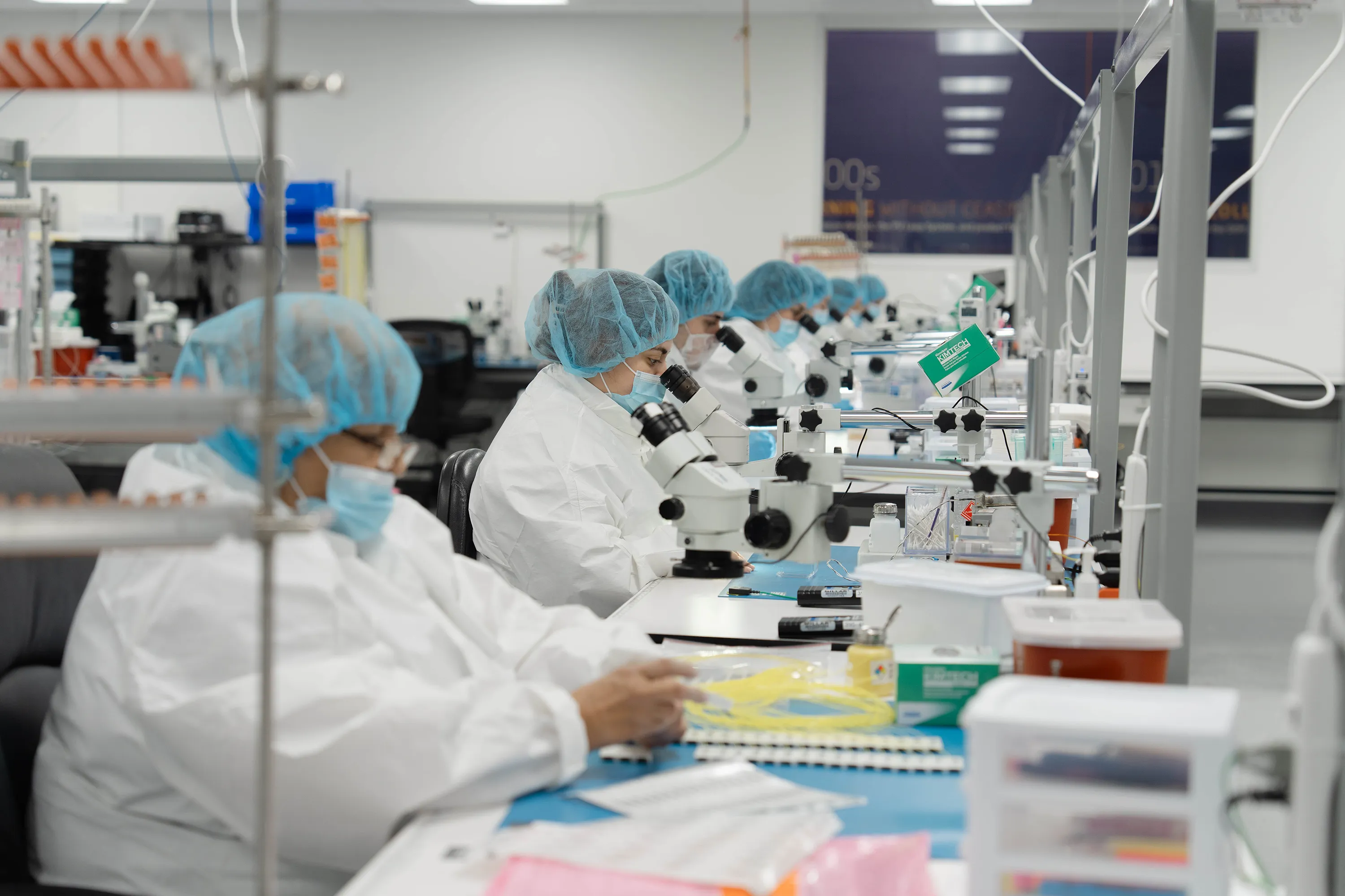 Millar employees wearing protective gear peer through microscopes in Millar’s ISO Class 7 clean room.