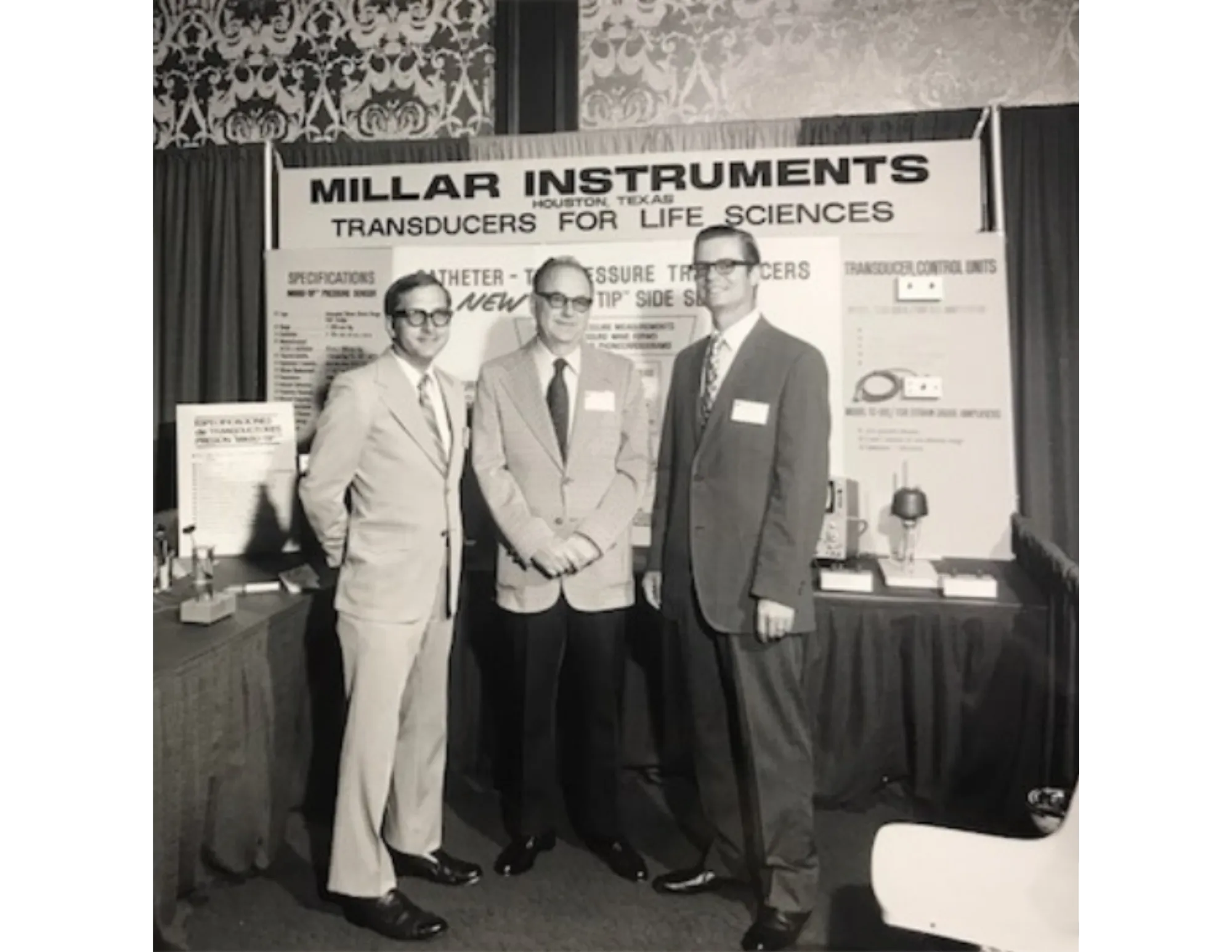 Millar founder, Huntly Millar, stands with two early Millar employees in front of Millar’s booth at a medical convention, circa 1970s. 