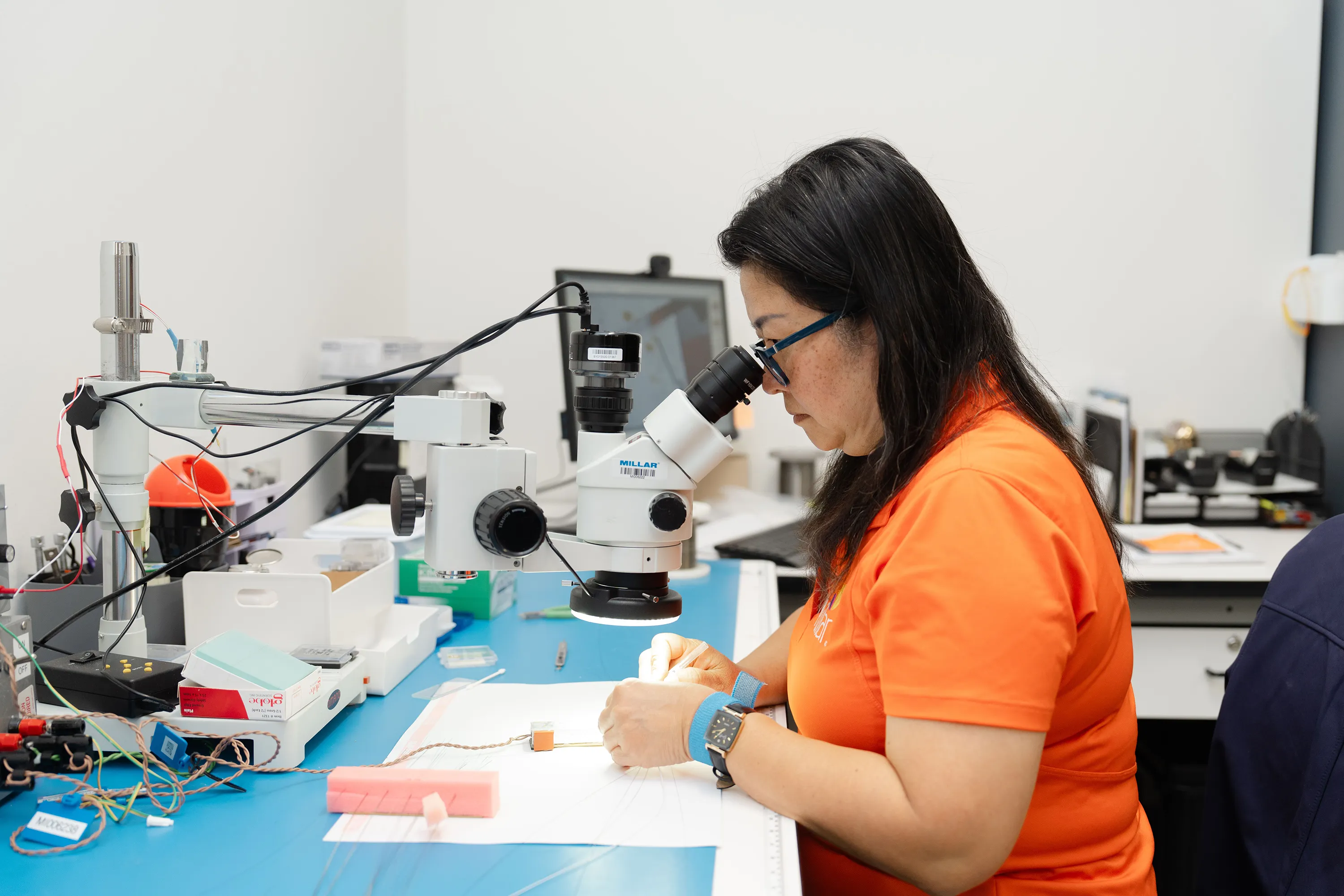 A Millar employee examines a sensor through a microscope. 