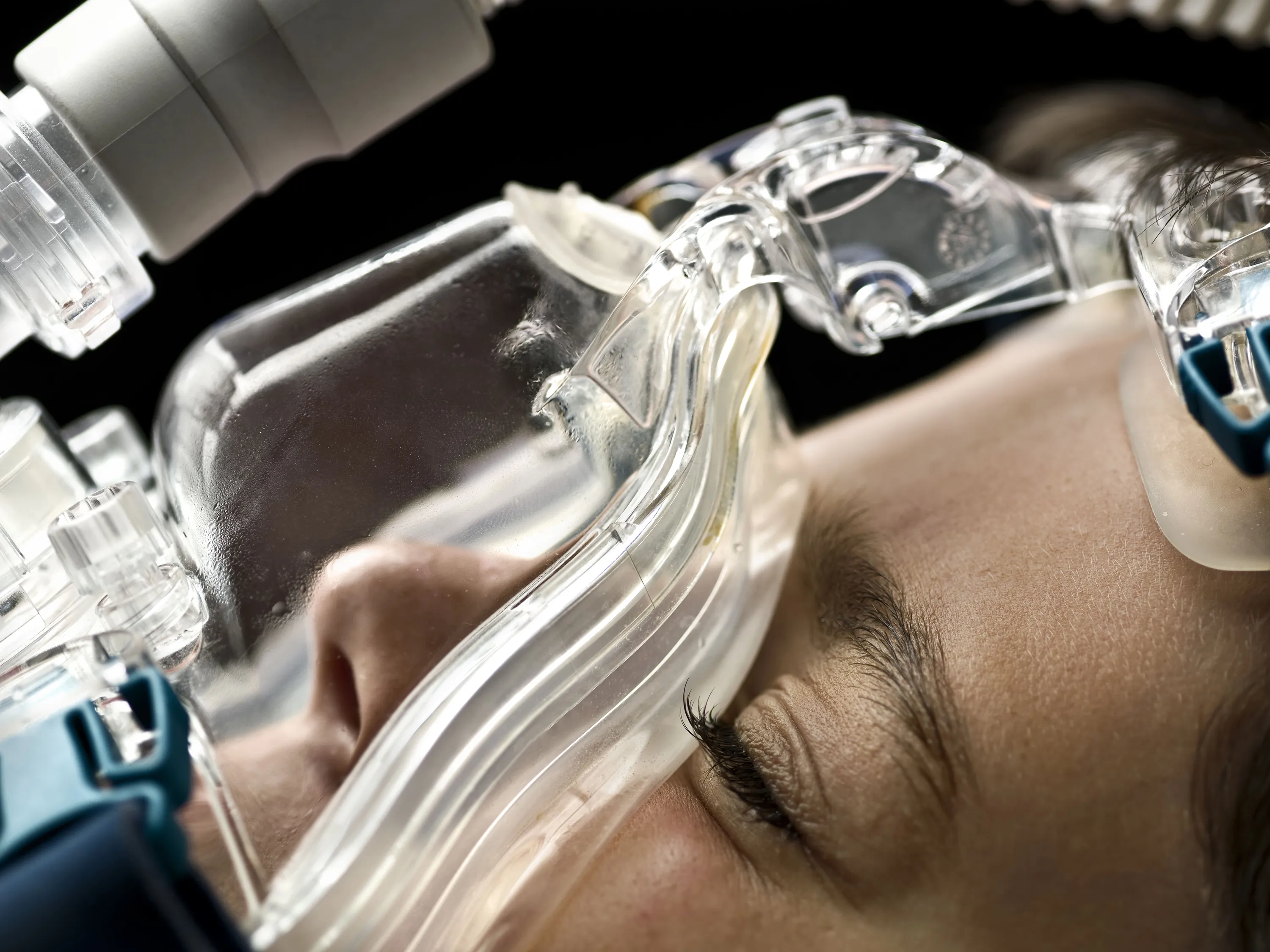 Close-up of a patient wearing a clear respiratory mask, representing the clinical application of advanced medical technology,
