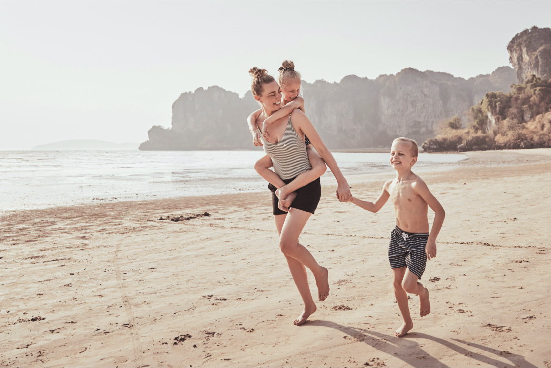 Mom and two children enjoying a walk down the beach.