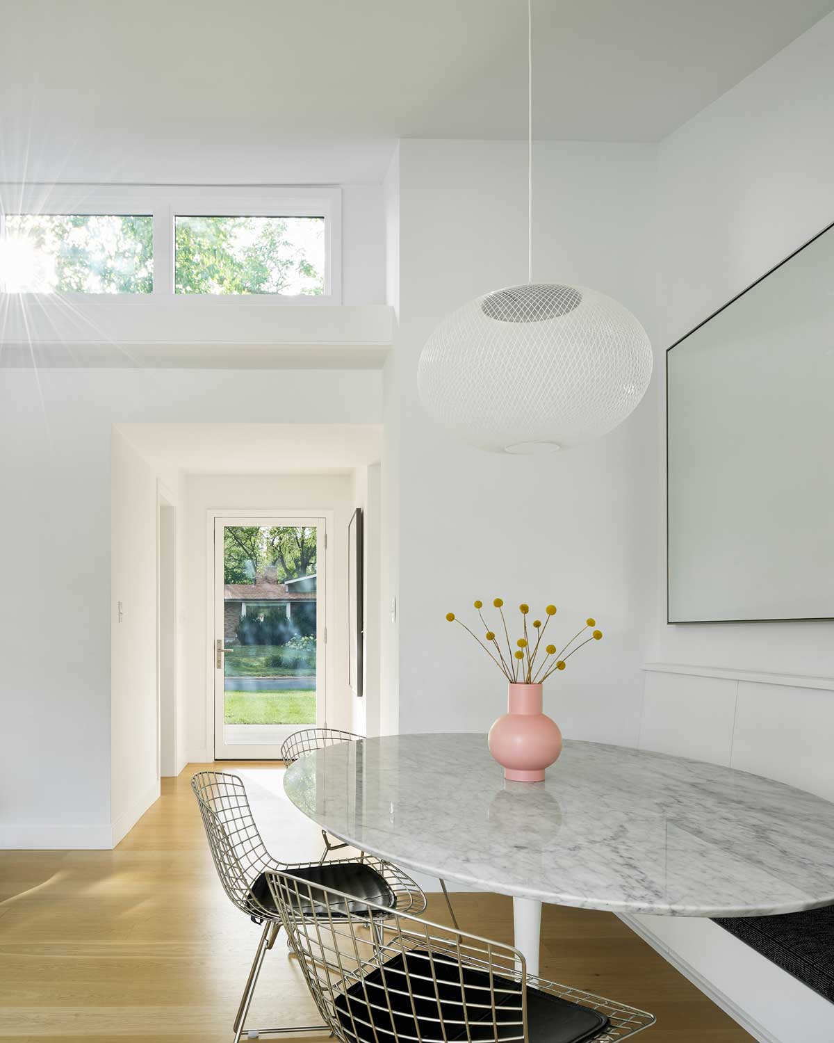 White dining room with glass table and architectural windows