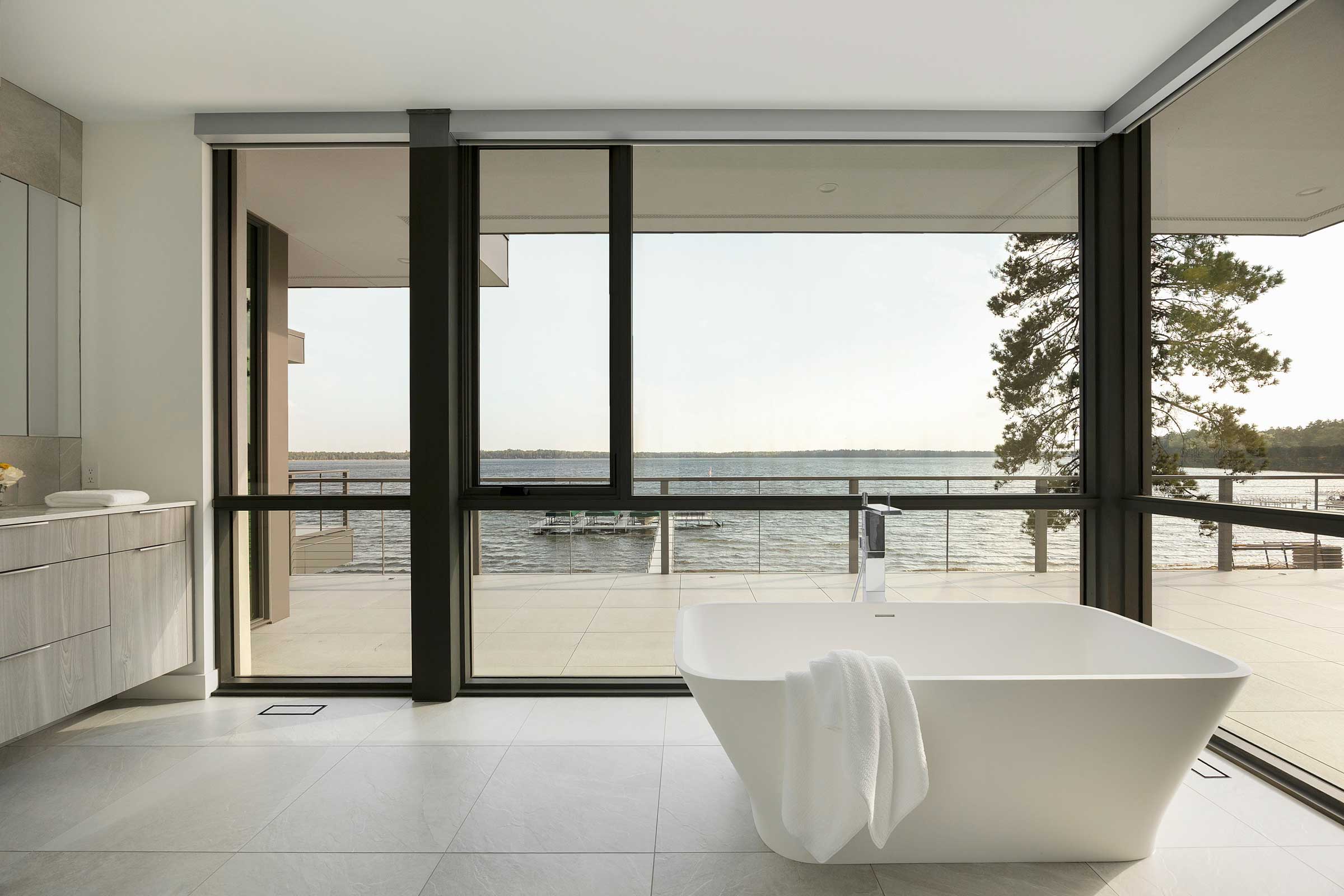 Modern bathroom with white soaking tub looking at lake