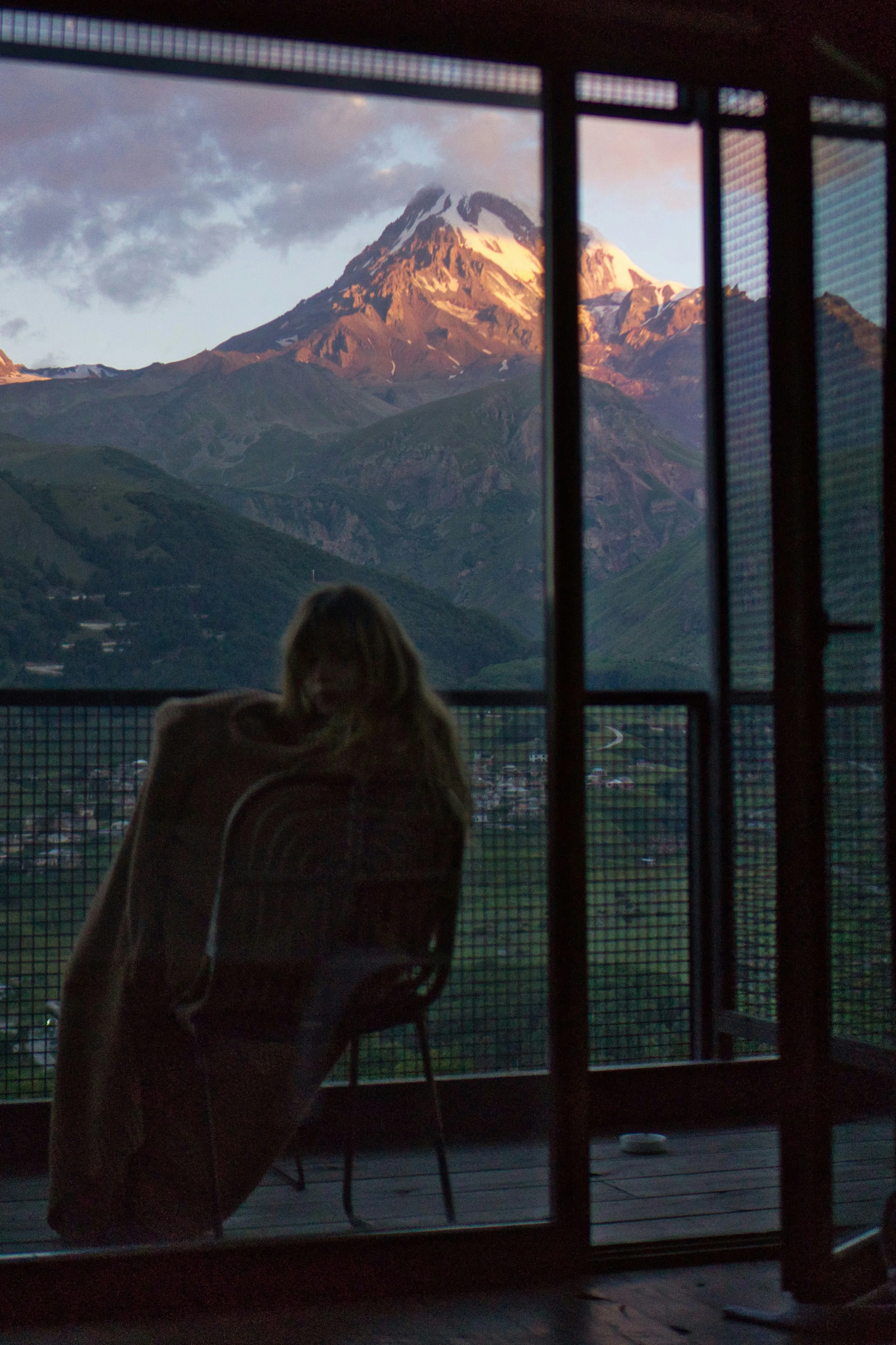 A pensive girl looking out at the mountain outside the window