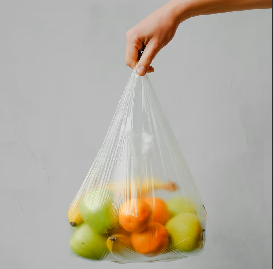 hand holding plastic bag full of fruit
