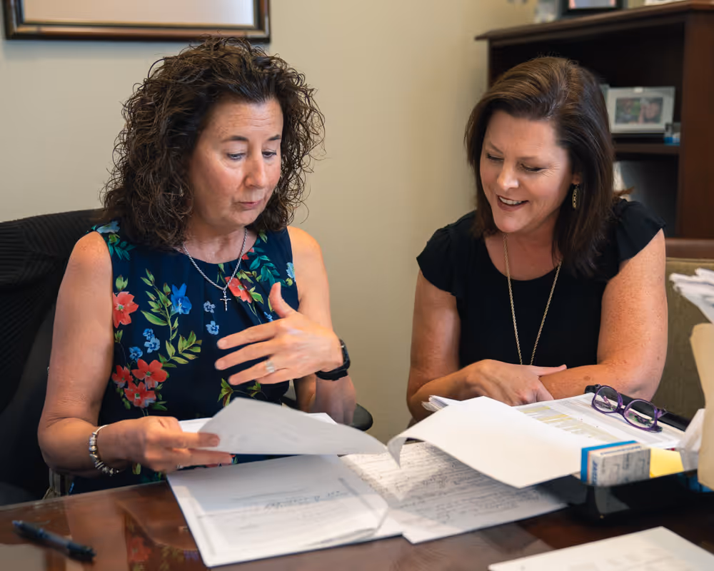 Two Lewis Mohr employees discussing insurance at a desk