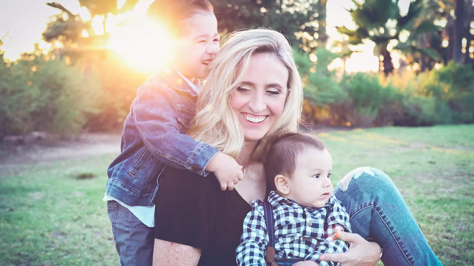 Mom with two children sitting and playing at sunset