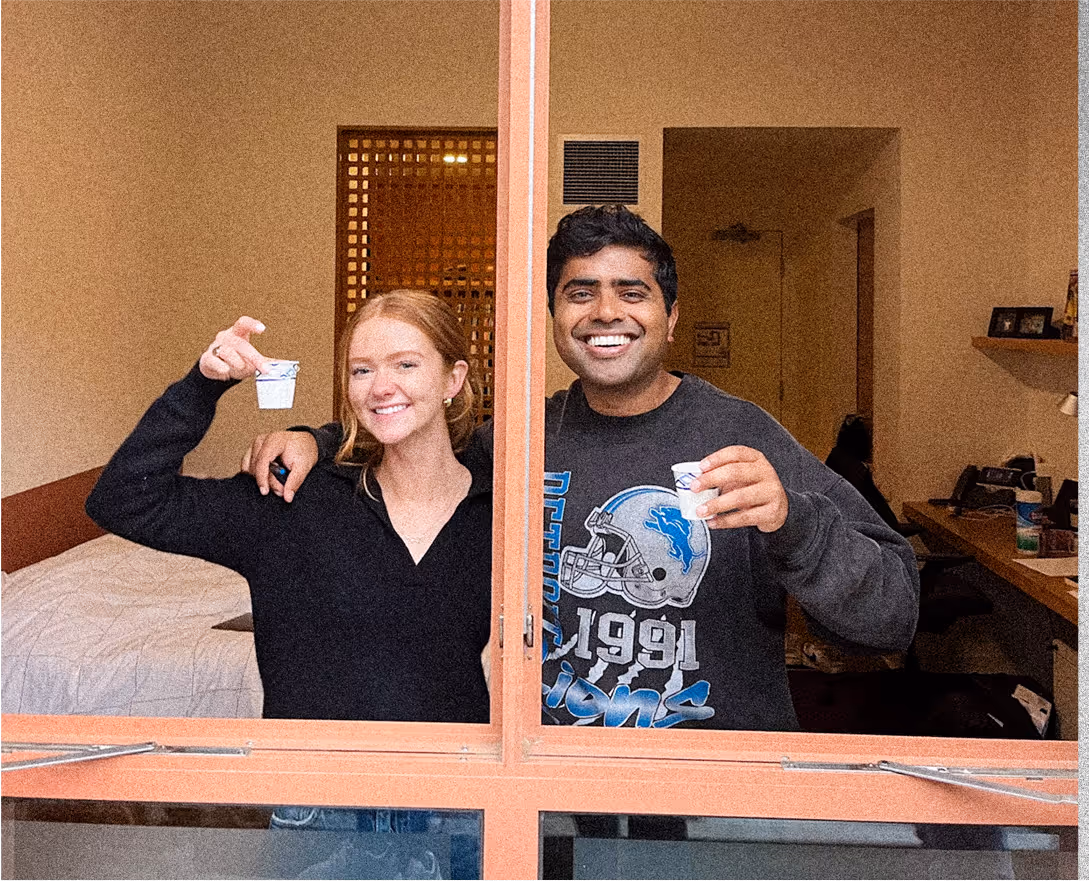Two friends hold a cup of what's likely the first versions of Goldi Locks and smile at the camera.