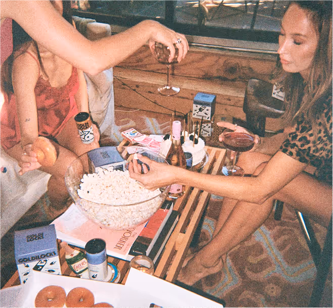 A group of friends hold drinks around a table.