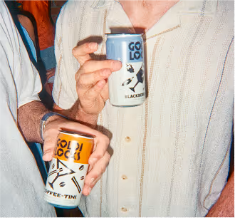 Two people torsos, their hands are holding cans of Goldi Locks.
