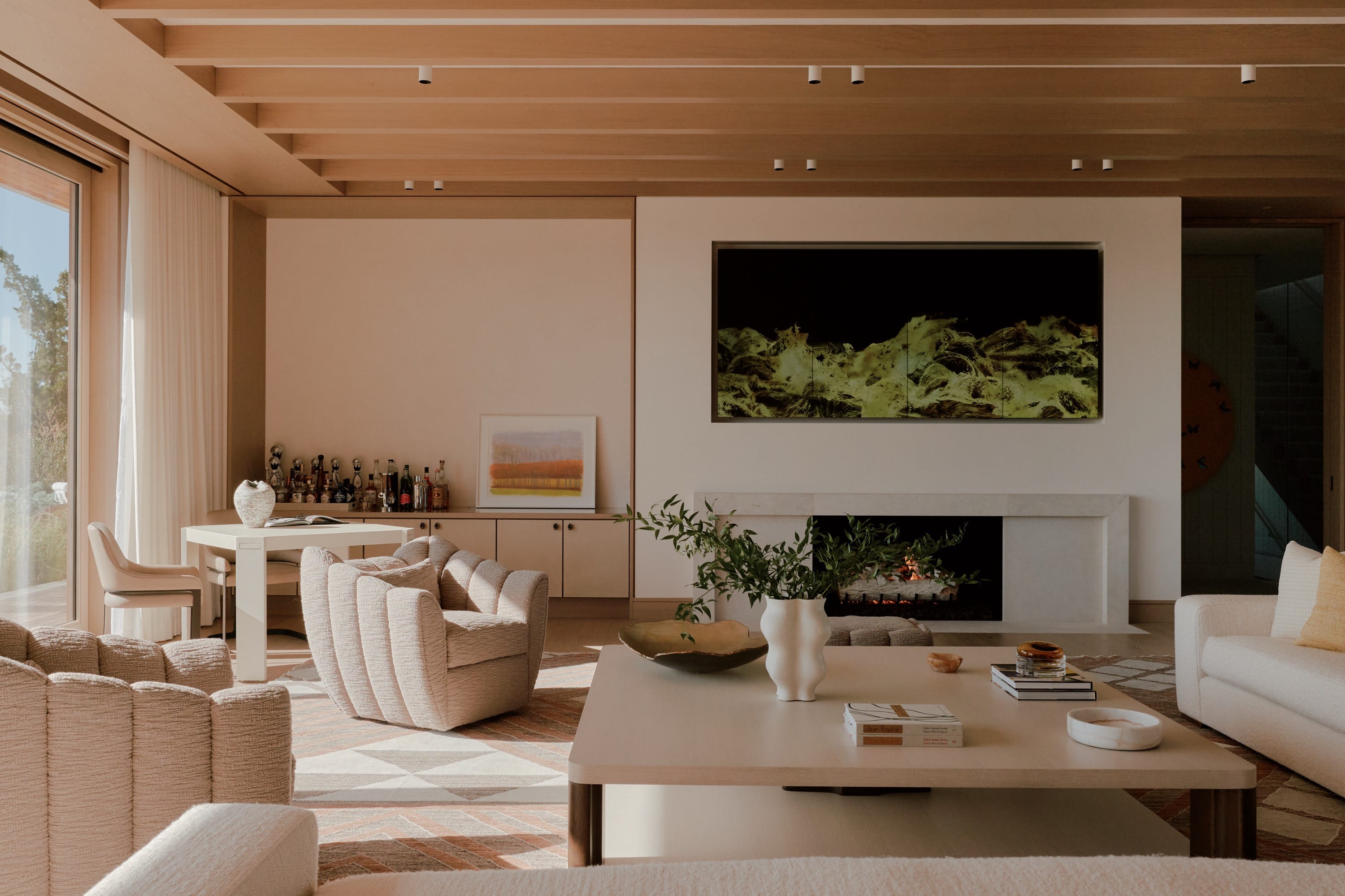 Modern living room with neutral furniture, fireplace, wall art, and built-in bar area.