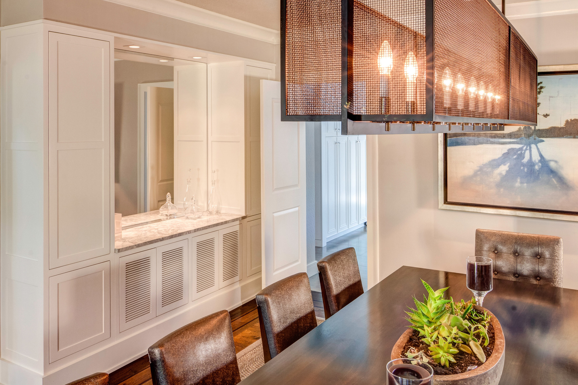 Dining area with white paneled walls and framed artwork.