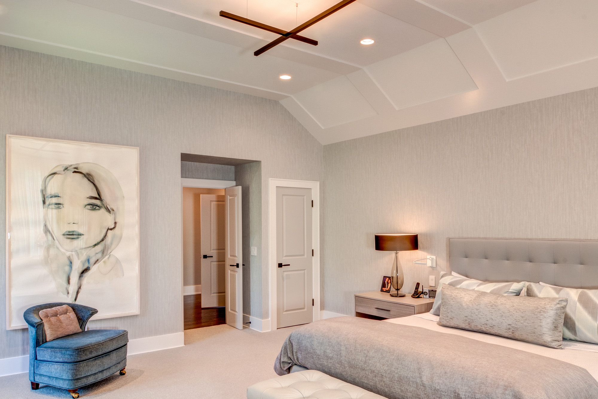 Bedroom with large bed, armchairs, and tray ceiling.
