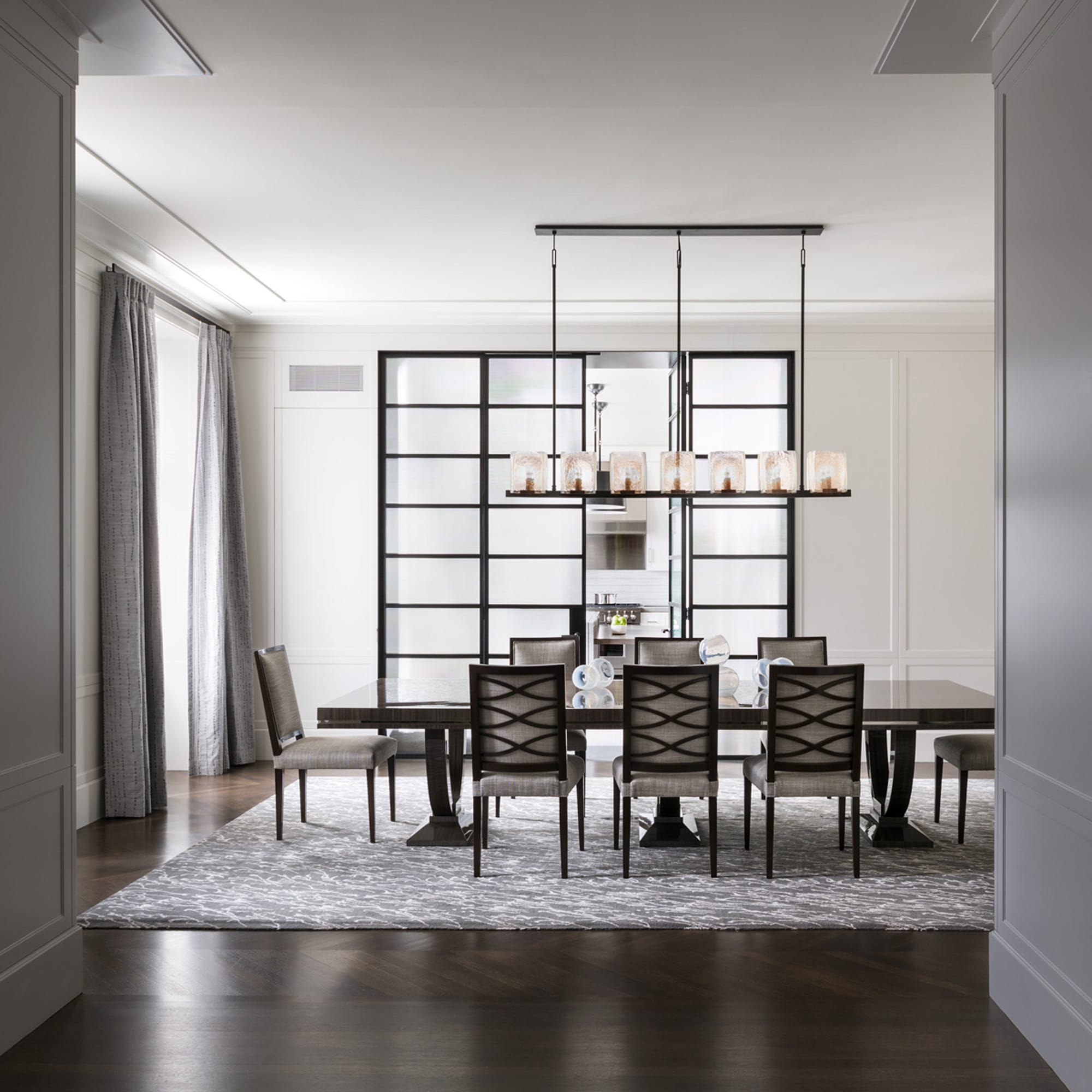 Dining room with dark table, chairs, and glass divider.