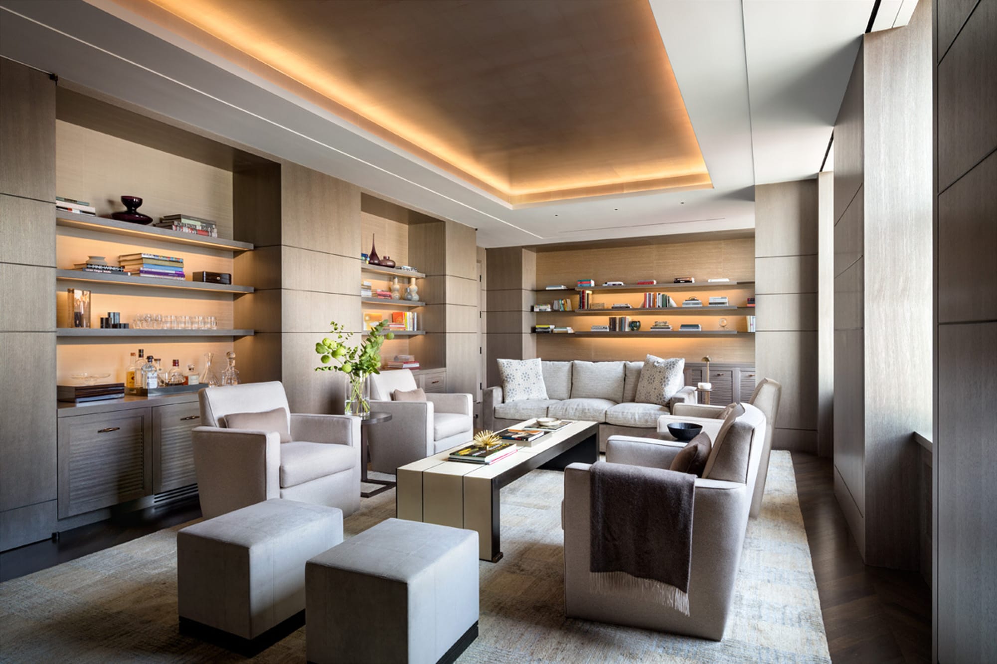 Lounge with built-in shelves, sectional sofa, and warm lighting.