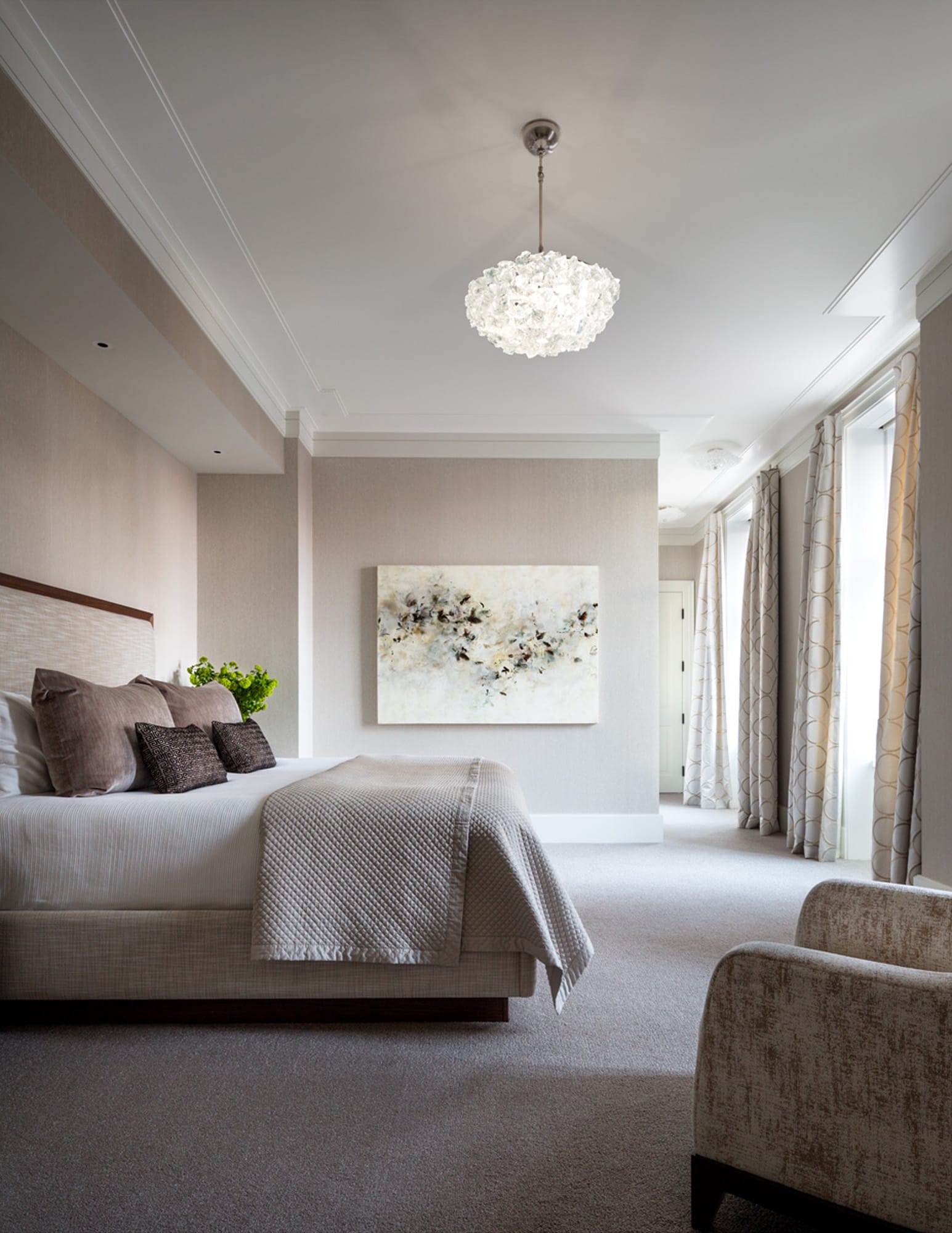 Bedroom with chandelier, upholstered bed, and seating area.