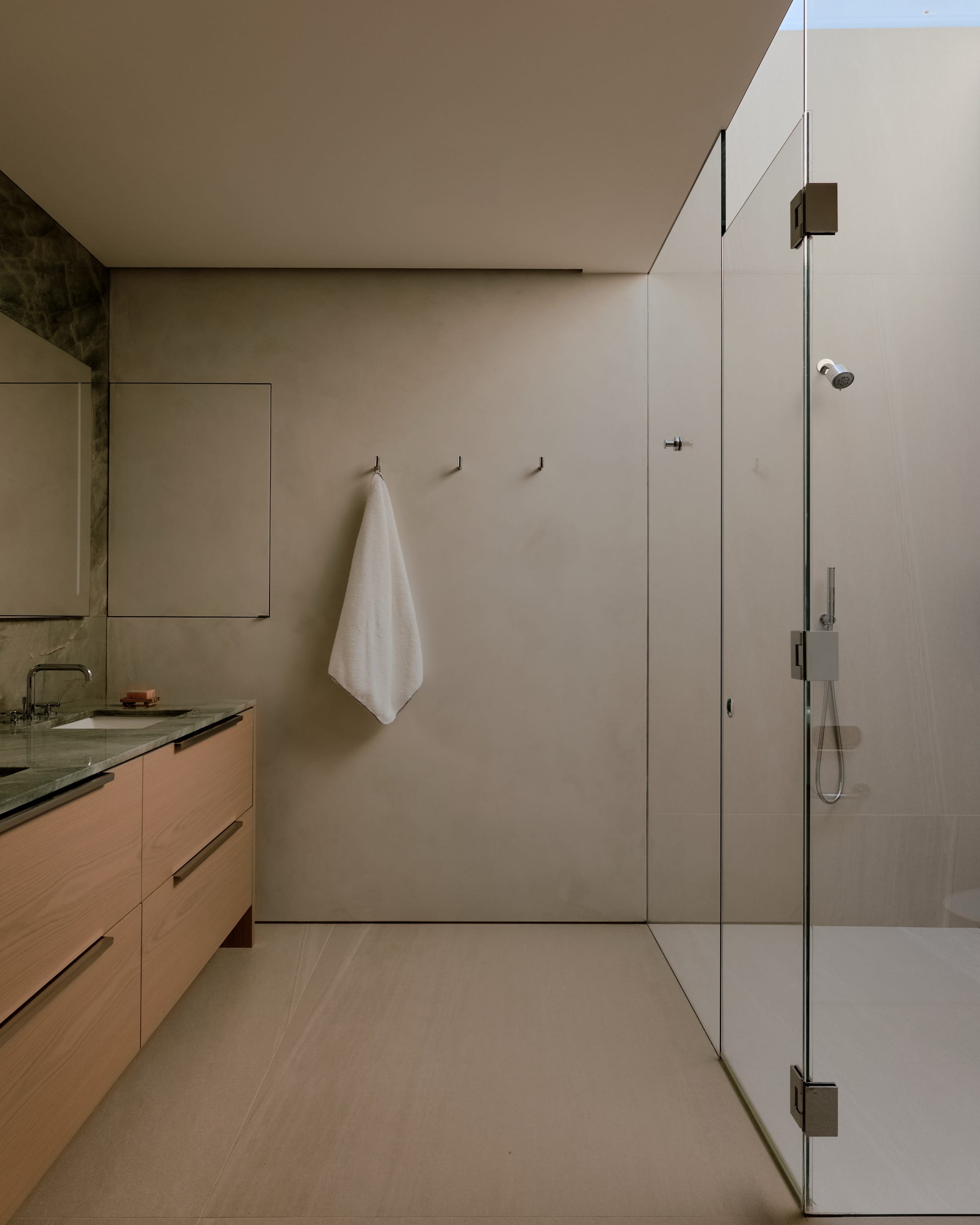 Bathroom with glass shower and light wood vanity.