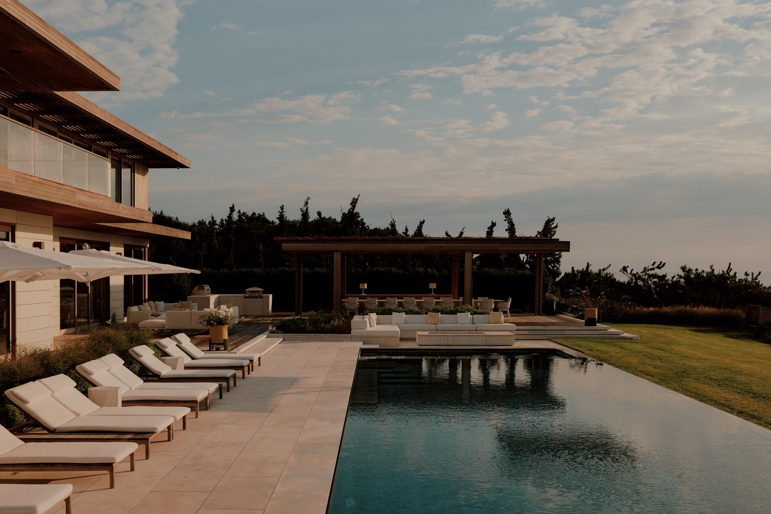 Poolside view with lounge chairs and modern home.