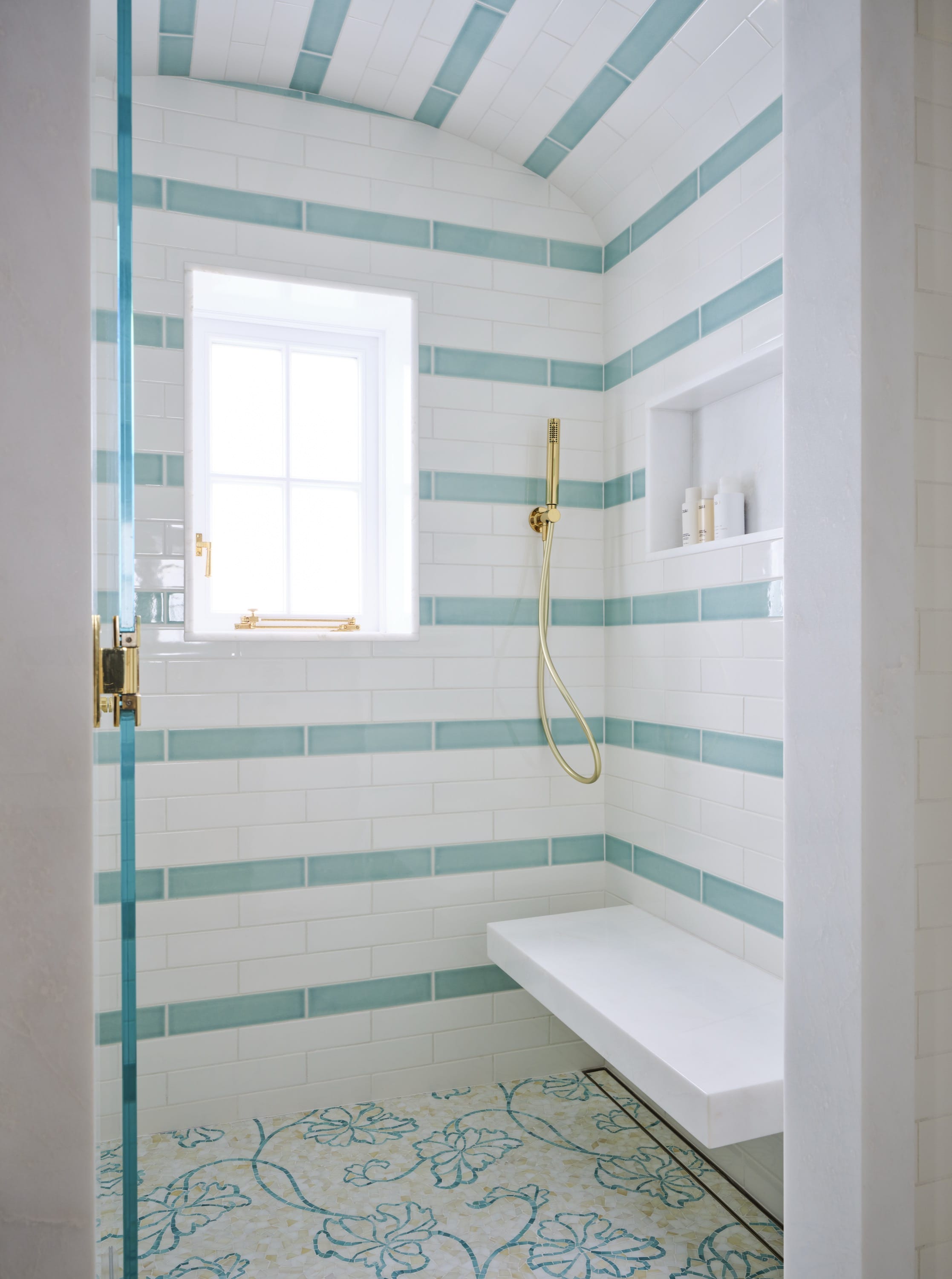 Bathroom with striped wallpaper and glass shower.