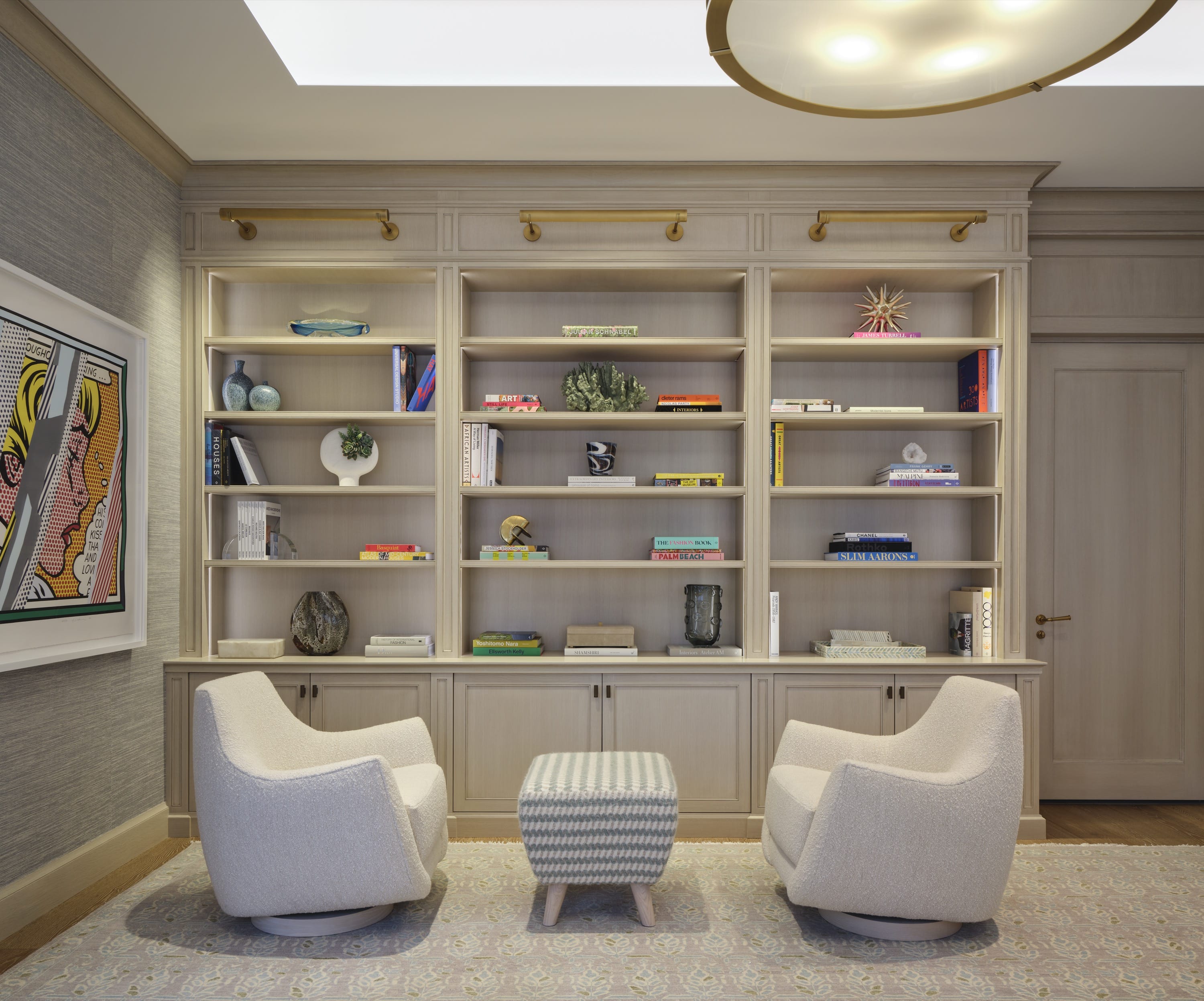 Library with built-in bookshelves and white lounge chairs.