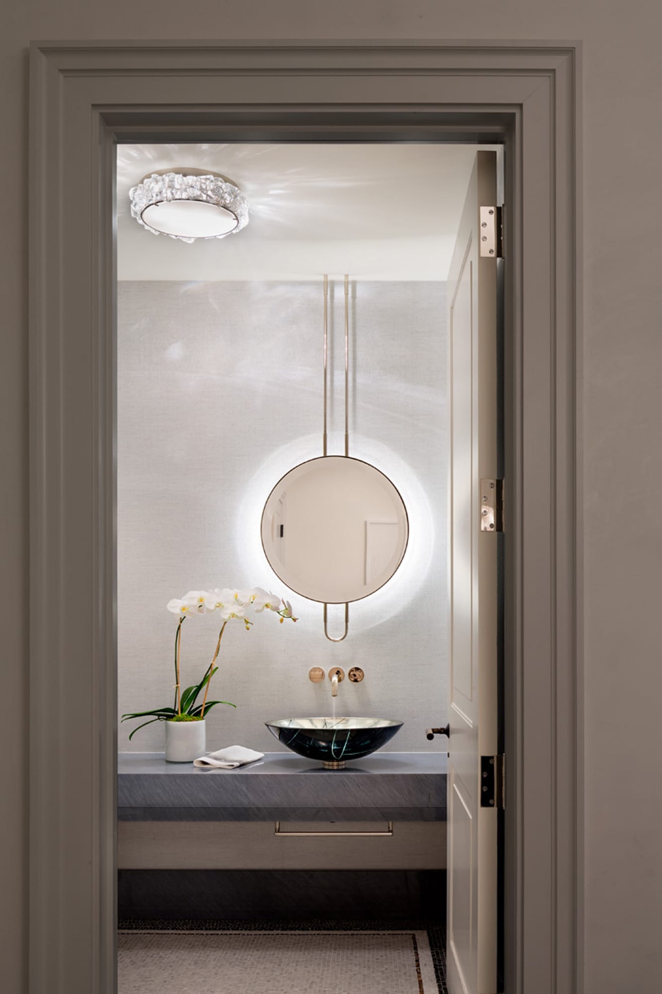 Powder room with circular mirror and wall sconce.