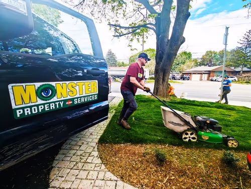 Male worker mowing lawn in front of a black truck