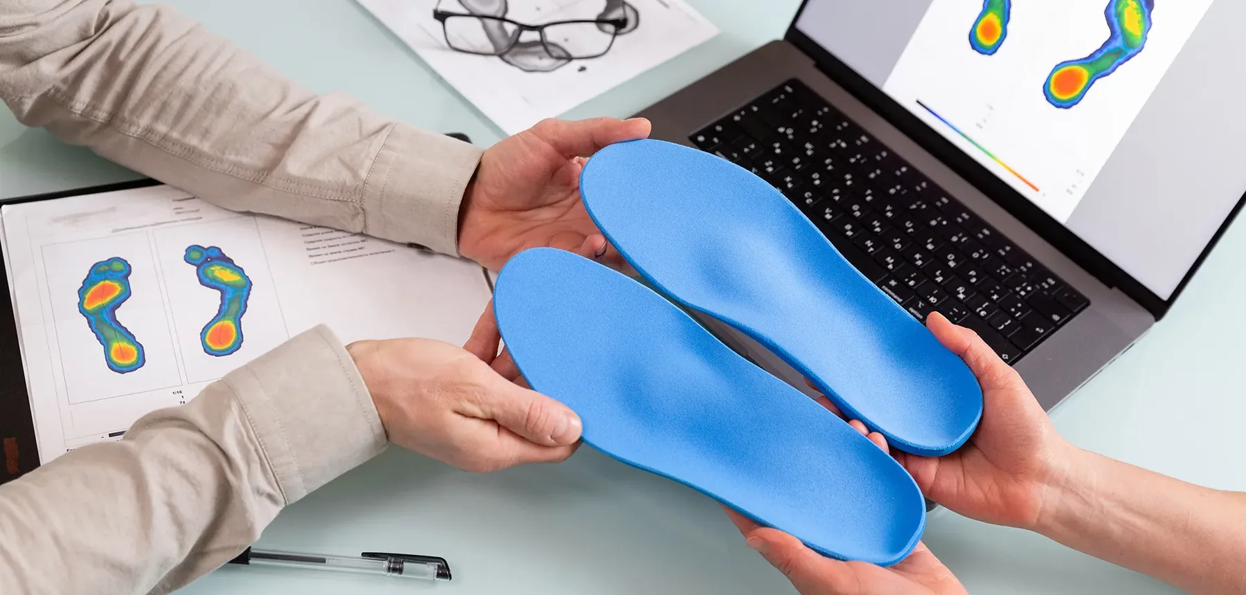 Skanowanie stóp pacjenta bezprzewodowym skanerem 3D na podwyższeniu, obok tablet z modelem 3D stóp