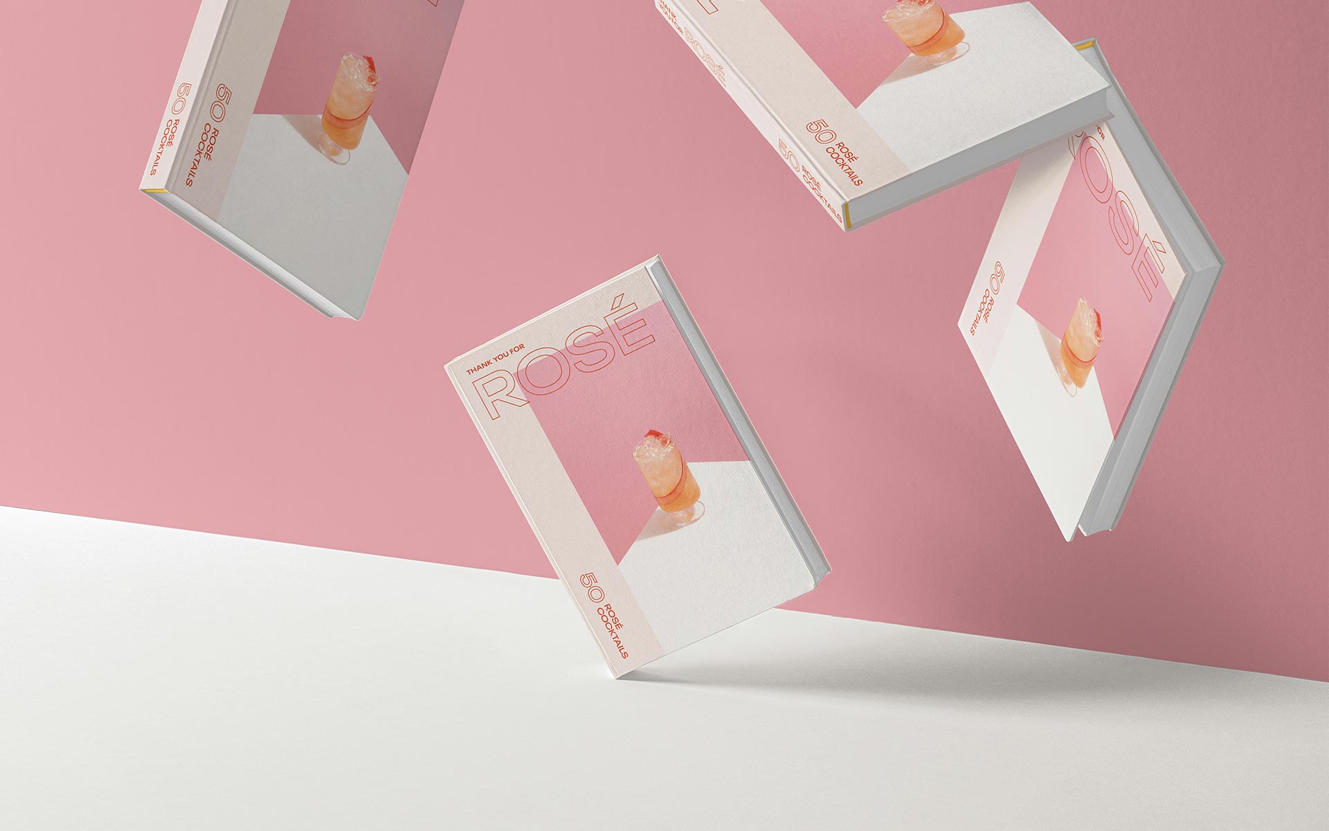 Books fall on a white table on a pink background.