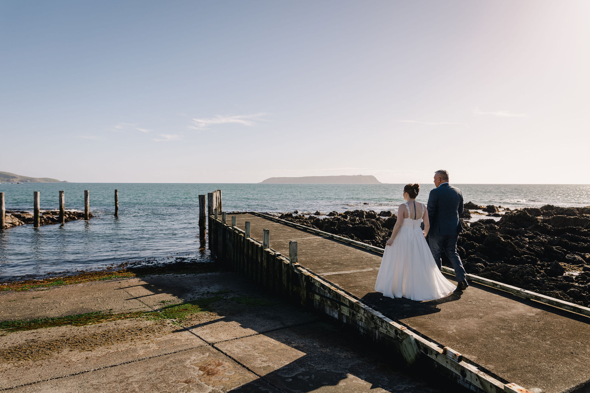 A newlywed couple on the jetty beside the sea at The Jetty, Plimmerton