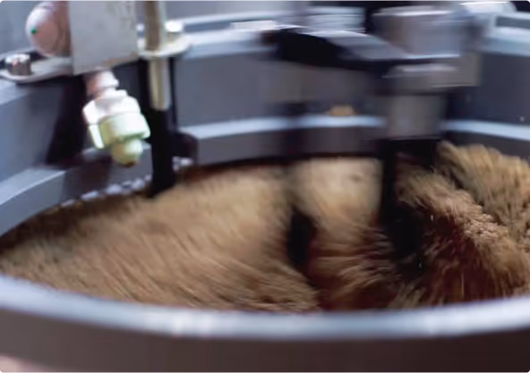 Close-up of coffee beans being roasted and stirred in a roasting machine.
