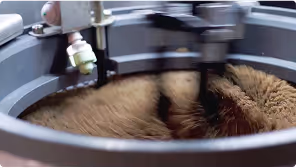Close-up of a machine stirring ground coffee inside a circular container.