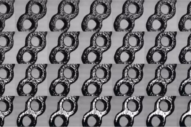 Close-up of a textured metal surface with a repeating pattern of interlocking figure-eight shaped links.