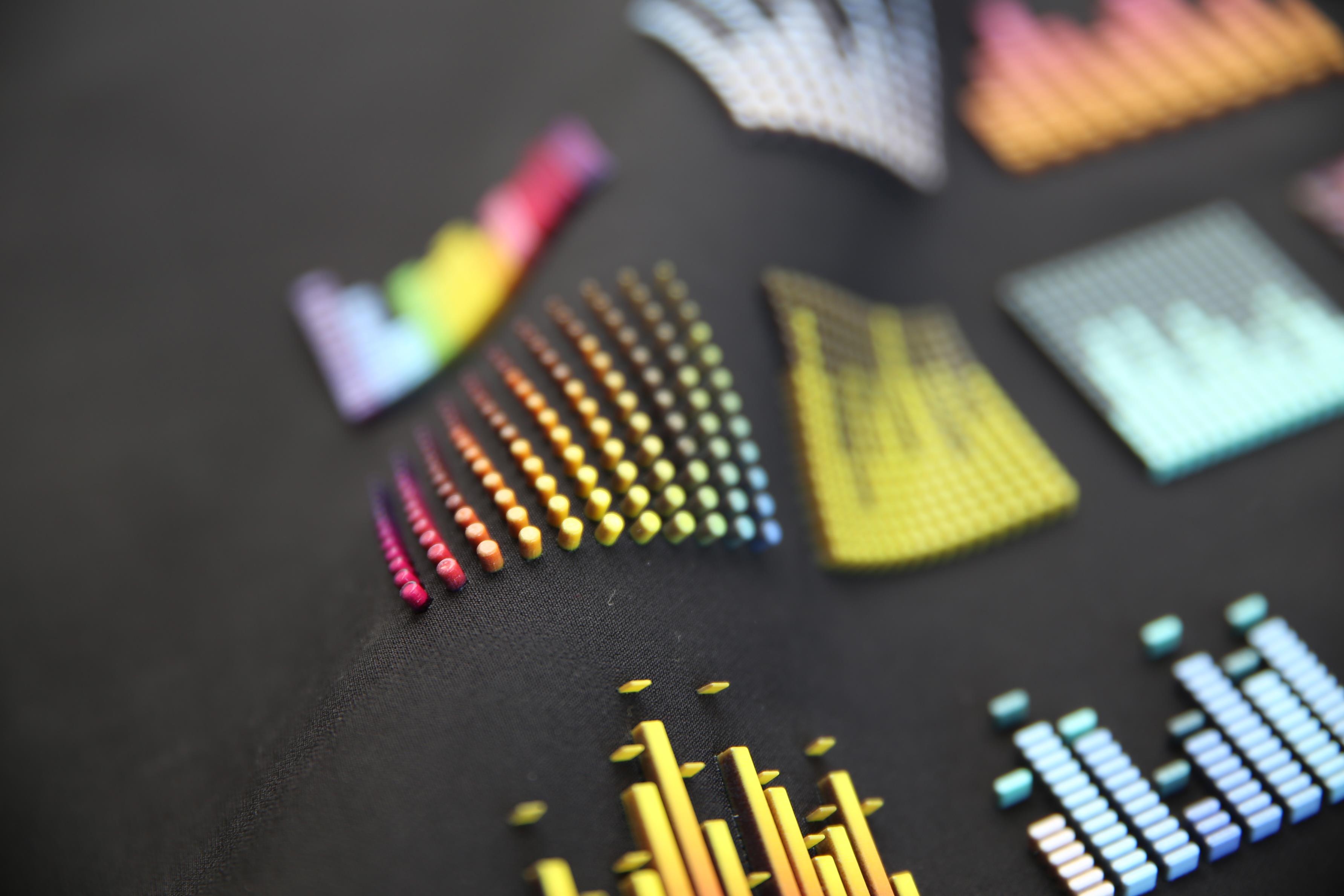 Close-up of colorful 3D bar graph patterns in various shapes on a black fabric surface.