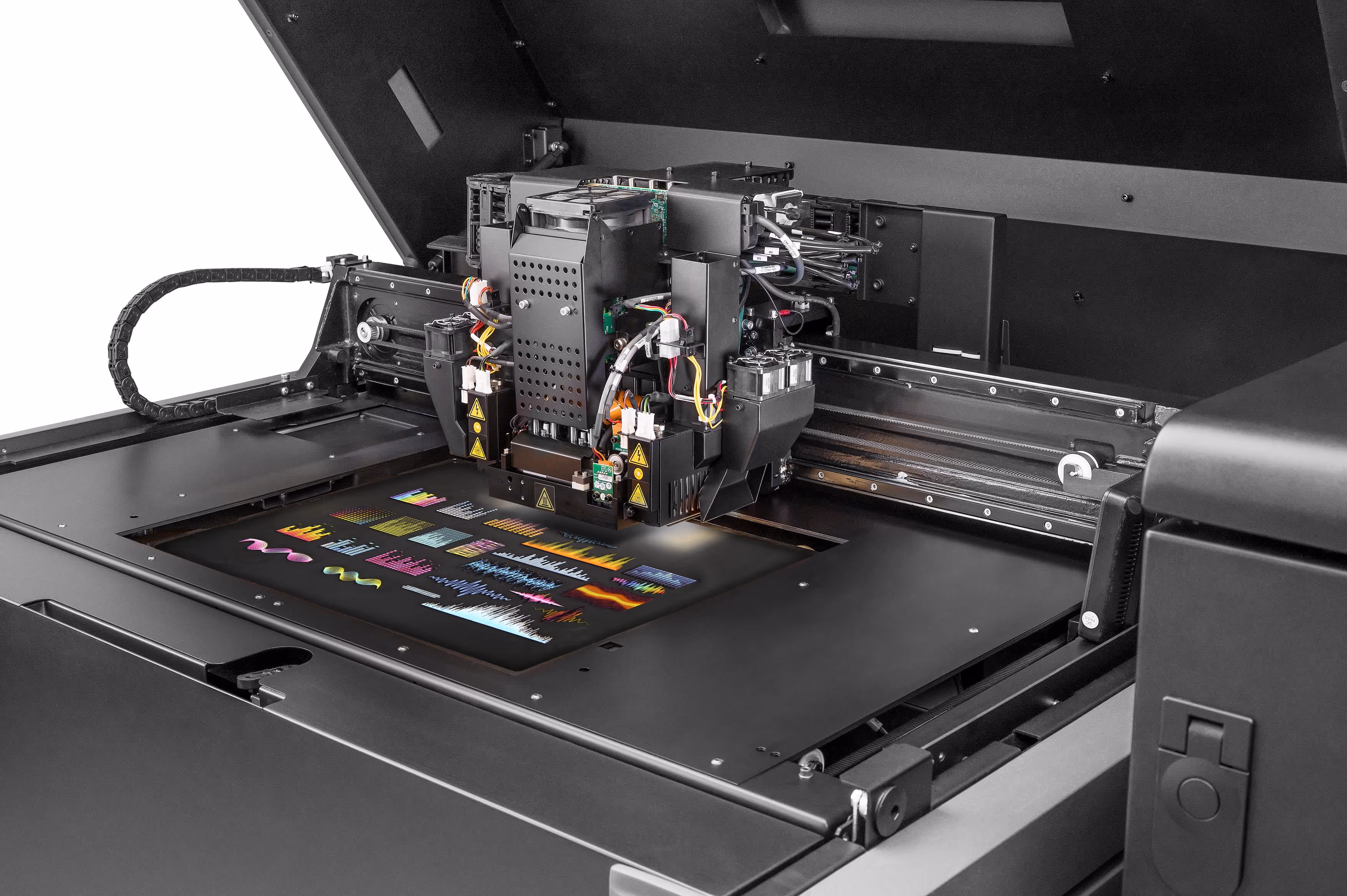 Close-up of a large black digital printer producing a colorful patterned print on a flat surface.