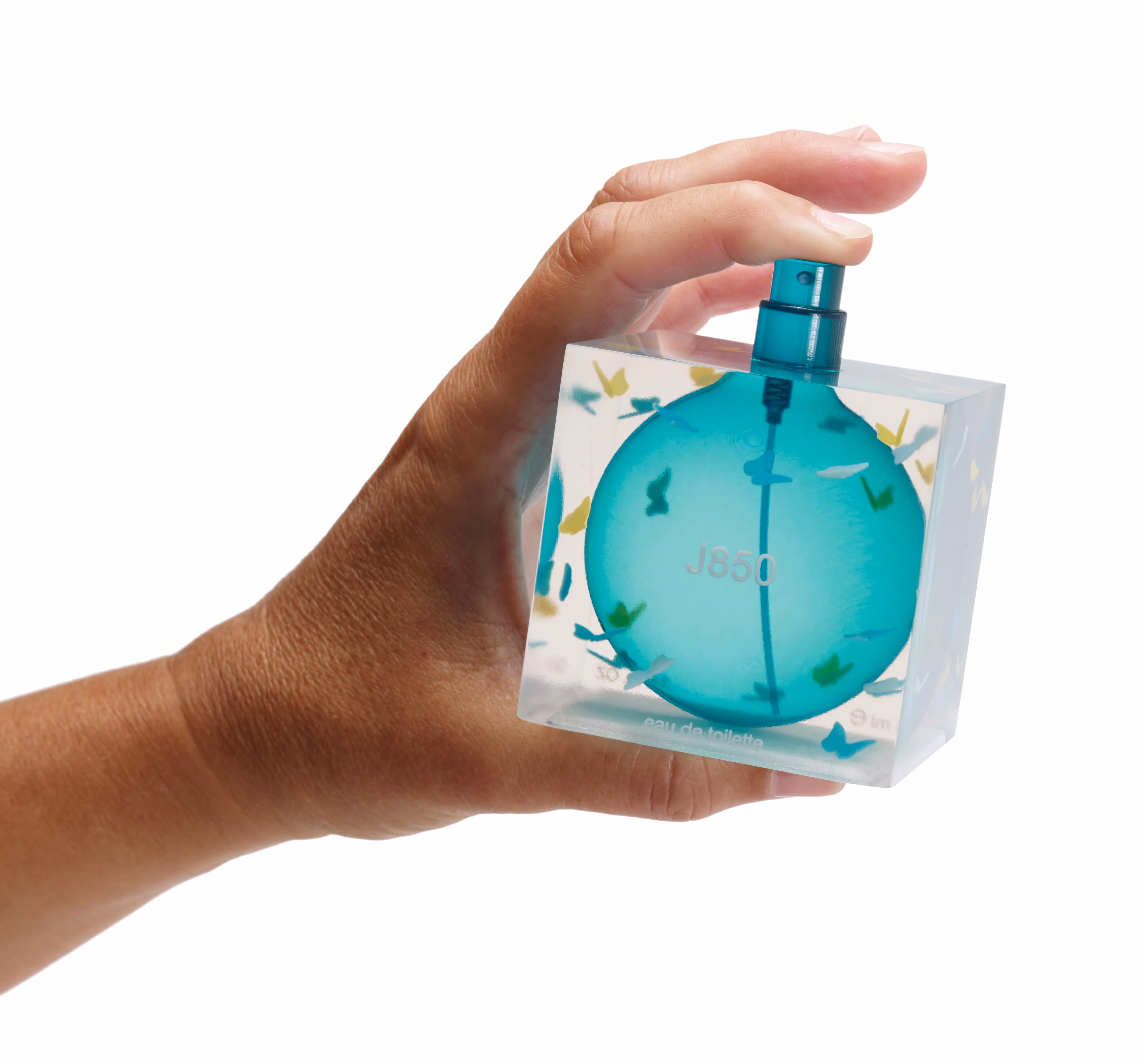 Hand holding a square perfume bottle with a blue spherical center and butterfly designs.